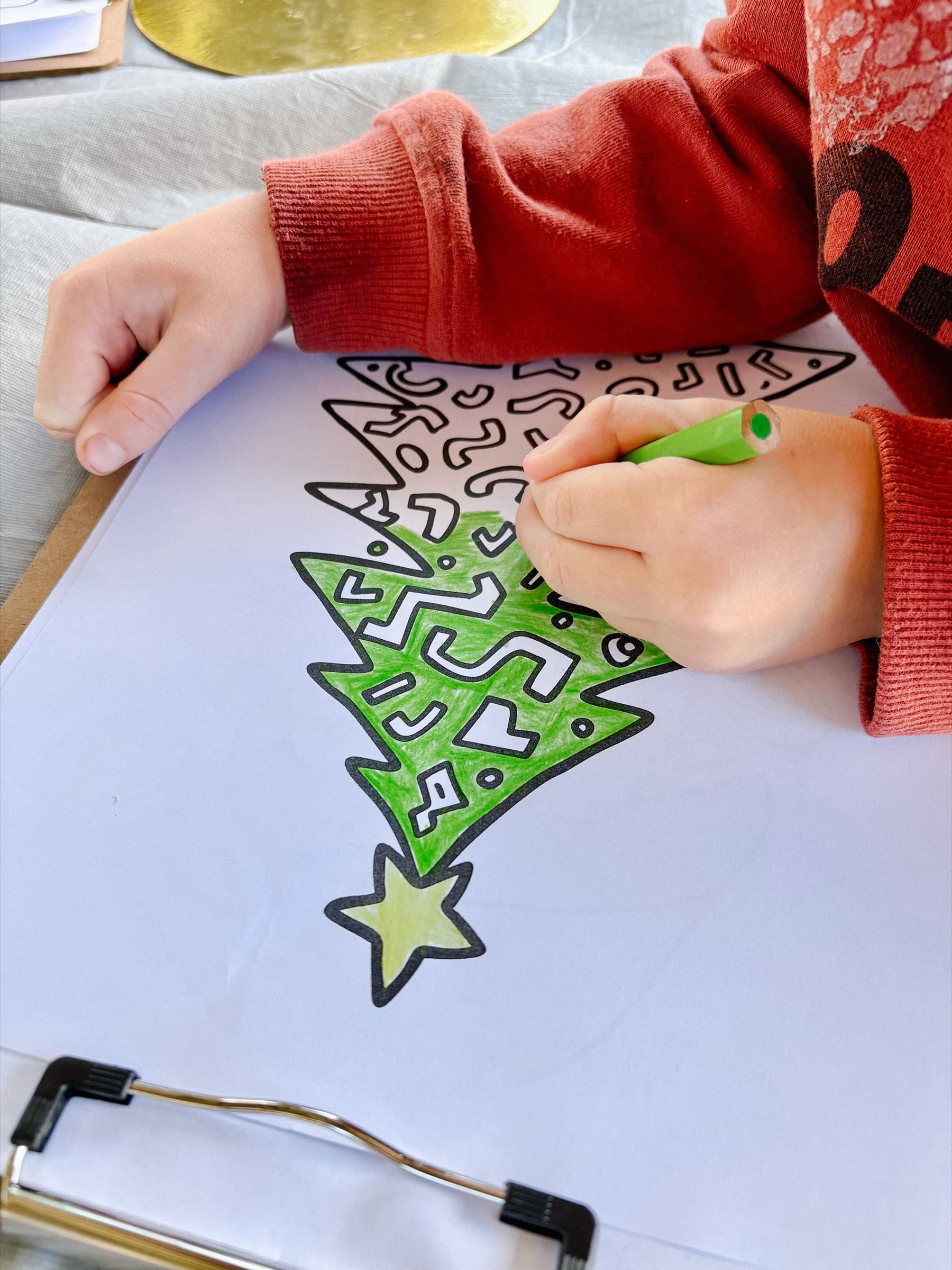Child colouring a Christmas tree illustration with a green marker at an Event Sitters craft session