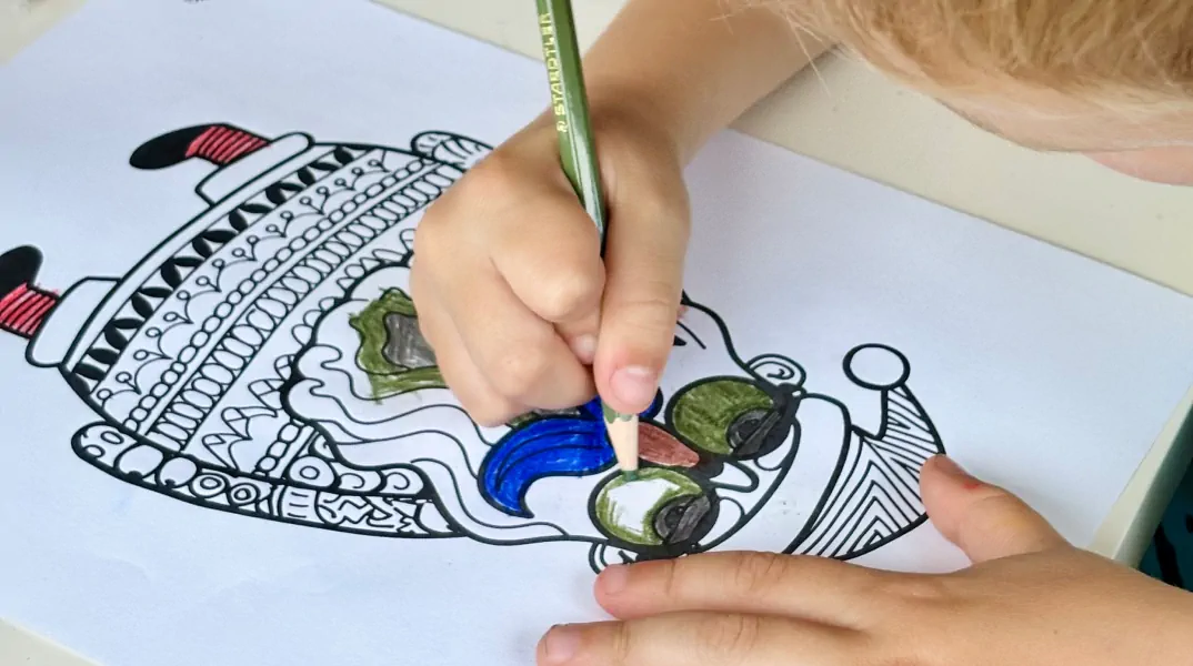 Child colouring a detailed craft design with bright pencils, focusing on fine artistic work.